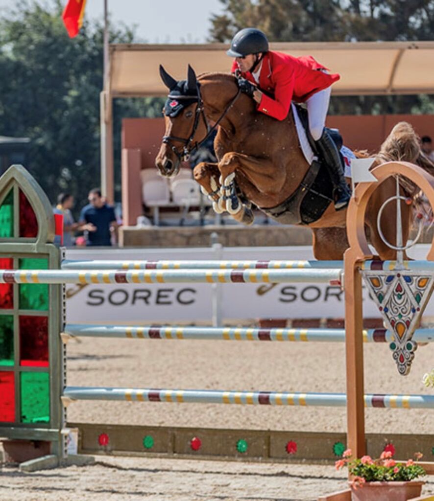 Chris Sorensen jumping a horse over a fence in a high level showjumping course